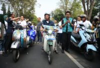 Penjabat Gubernur Bey Machmudin menaiki motor bekjul hijau yang telah dikonversi jadi kendaraan listrik saat konvoi EV Fun Carnival - West Java Festival 2024 di Jalan Diponegoro, Kota Bandung, Jumat (23/8/2024).